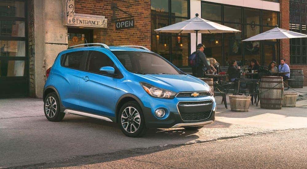 A blue 2017 Chevy Spark is parked in front of a cafe.