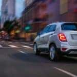 A silver 2021 Chevy Trax is shown from behind driving through the city after leaving the Capital District Chevy dealership.