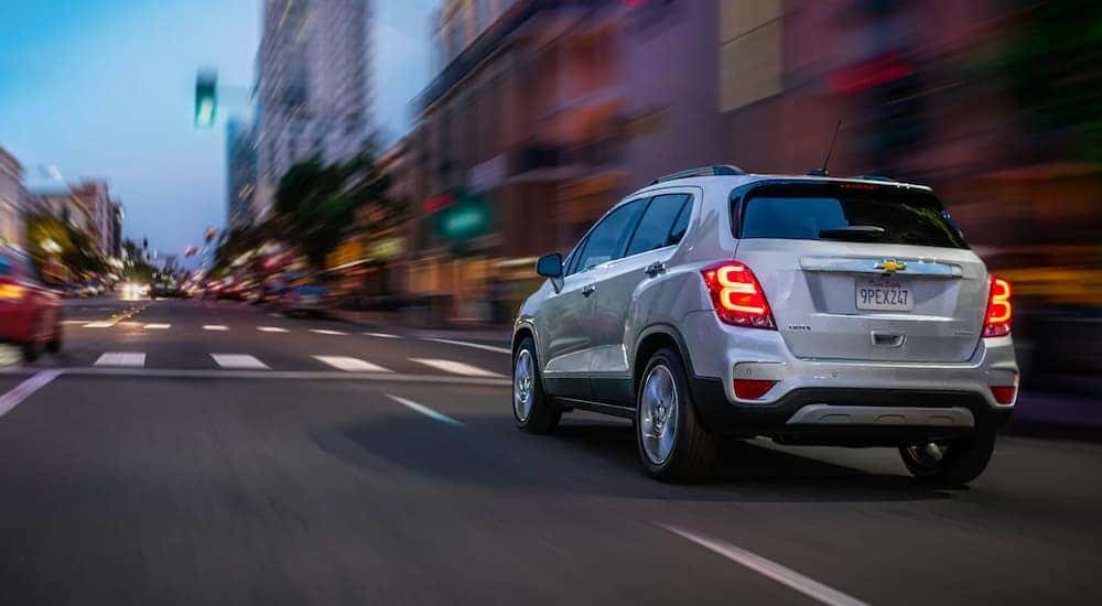 A silver 2021 Chevy Trax is shown from behind driving through the city after leaving the Capital District Chevy dealership.