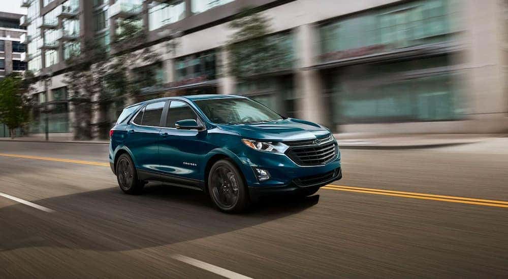 A blue 2021 Chevy Equinox is driving through the city after leaving a Clifton Park used car dealer.
