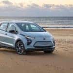 A pale blue 2022 Chevy Bolt EV is parked on a beach.