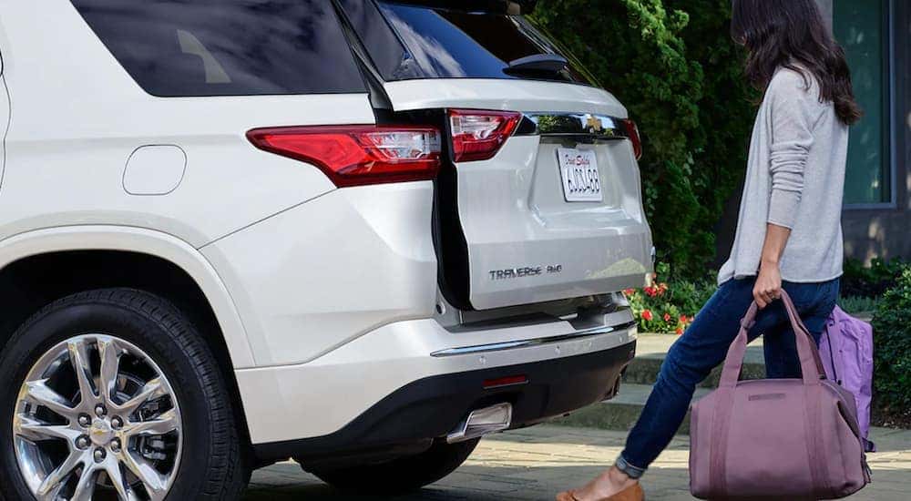 A white 2021 Chevy Traverse is shown from behind with the a woman opening the trunk.