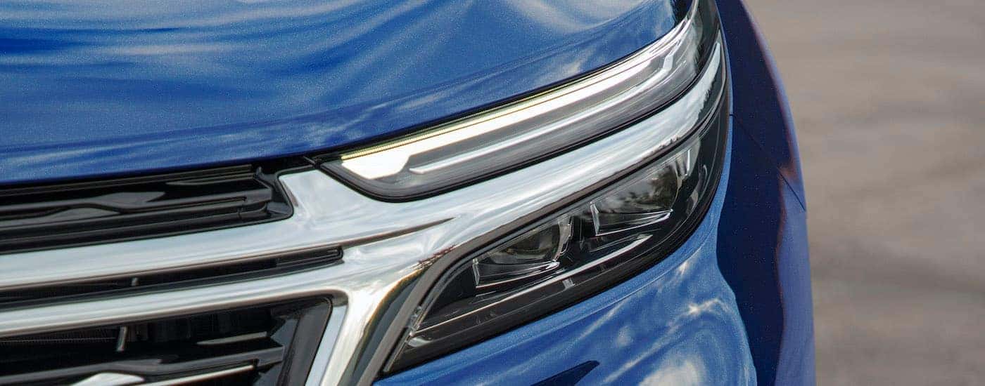 A close up shows the driver side headlight on a dark blue 2022 Chevy Equinox Premier.