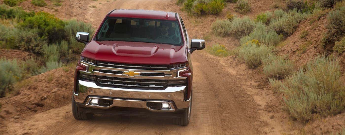 A red 2021 Chevy Silverado is shown from the front driving on a dirt trail.