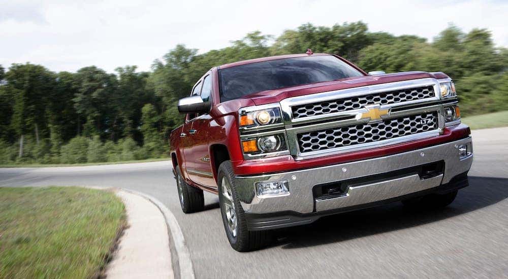 A closeup shows a red 2017 Chevy Silverado driving on a track after leaving a Certified Pre-Owned Chevrolet Dealer.