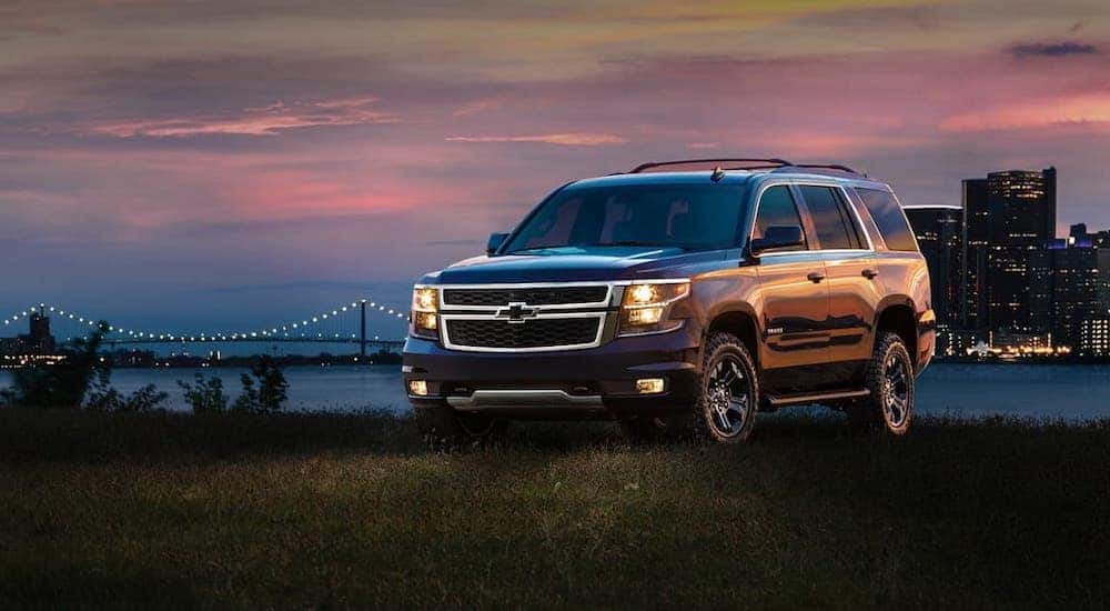 A black 2018 Chevy Tahoe is parked in front of a city at night.