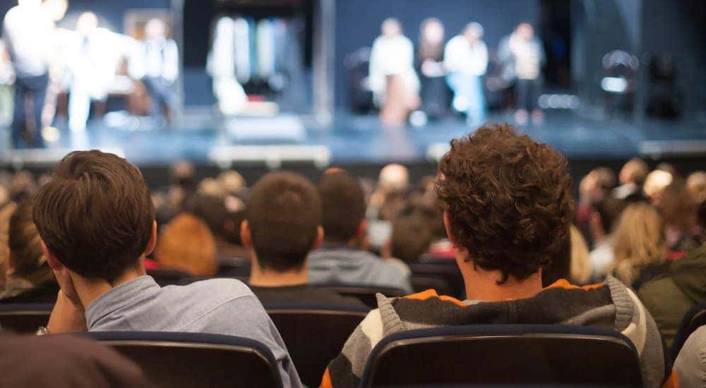 People are shown from the back watching a play at a Schenectady theater.