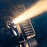 A film projector is shown against a dark background.