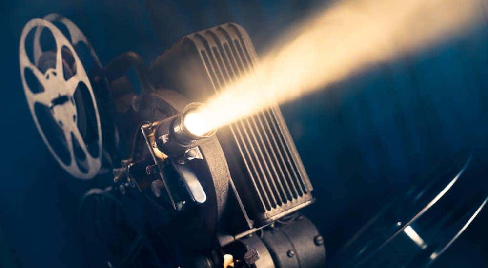 A film projector is shown against a dark background.