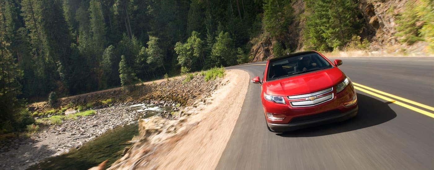 A red 2010 Chevy Volt is shown from the front speeding down a tree lined road.
