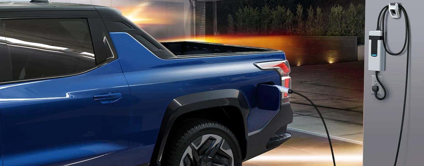 A blue 2024 Chevy Silverado EV is shown charging in a garage.