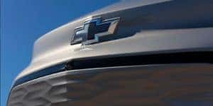 A close up shows the blue Chevy bowtie emblem on a gray 2022 Chevy Bolt EUV.