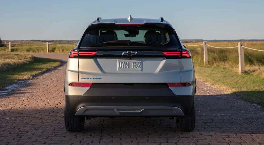A silver 2022 Chevy Bolt EUV is shown driving from the back on a path near the ocean.
