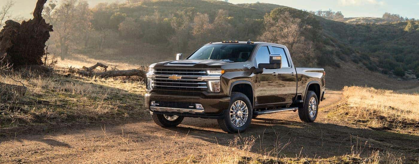 A black 2021 Chevy Silverado 2500 HD High Country is shown on a dirt path after leaving a Chevrolet Silverado HD dealer.