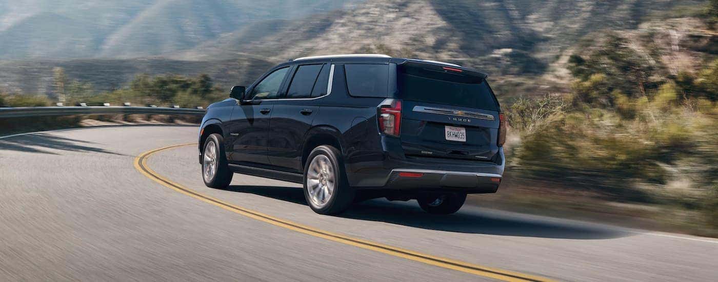 A black 2021 Chevy Tahoe is driving to a Chevy Tahoe dealership.