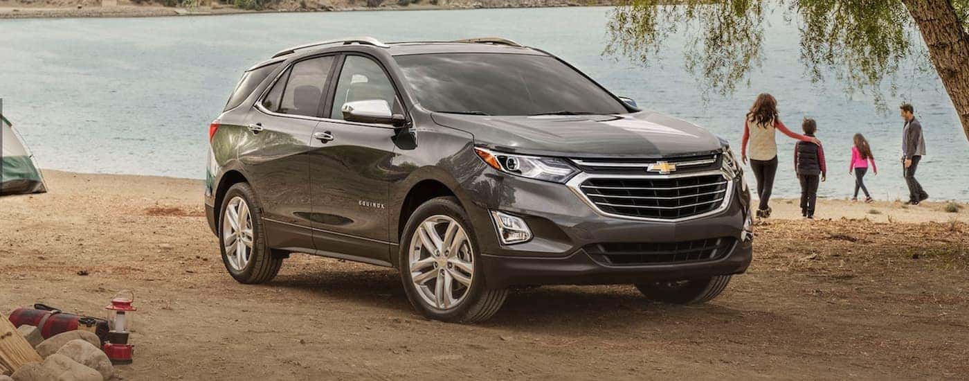 A grey 2021 Chevy Equinox is parked in front of a family at a lake.