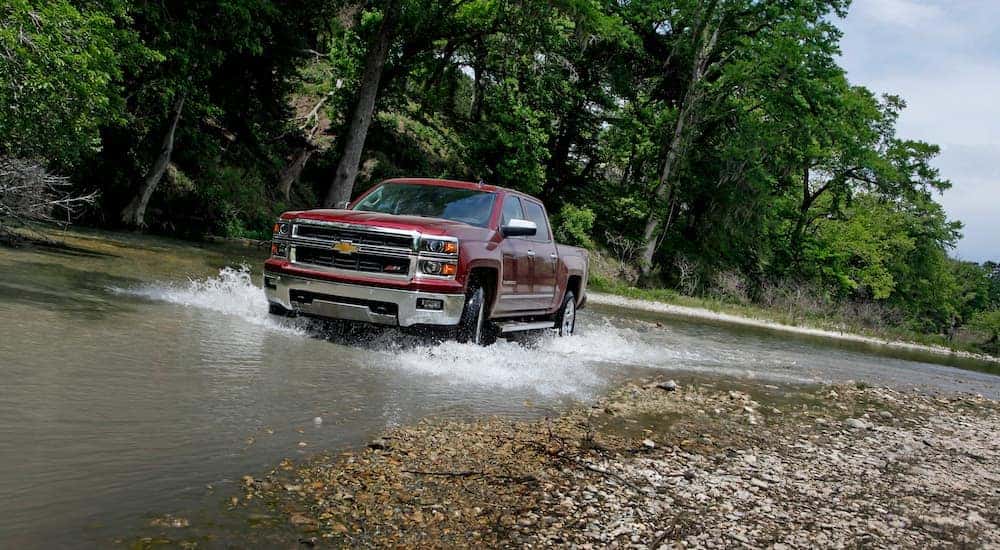 Front view of a red 2014 Chevy Silverado 1500 LTZ driving through a river
