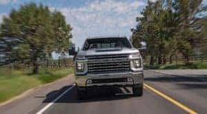 A silver 2020 Chevy Silverado 2500HD Z71 is shown from the front driving on the road after leaving a used Chevy truck dealership.