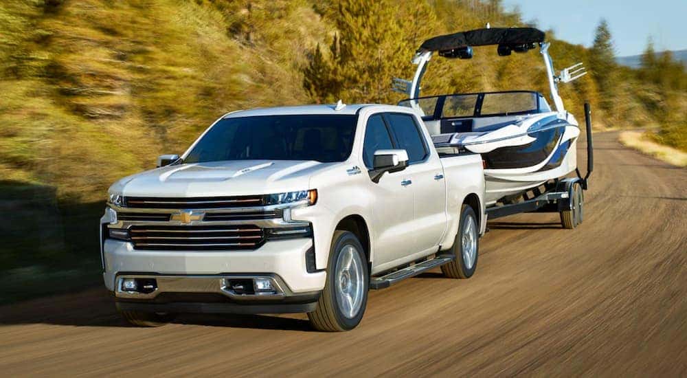 A white 2021 Chevy Silverado 1500 is towing a boat after leaving a Chevy 1500 diesel dealer.