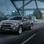A grey 2022 Chevy Colorado LT is shown driving over a bridge at night.