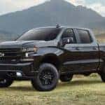 A black 2021 Chevy Silverado is shown from the front parked in front of a mountain range.