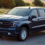 A black 2019 Chevy Silverado 1500 is shown from the side driving on an open road after looking for Chevy trucks for sale.