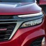 A close up of a red 2022 Chevy Equinox RS shows the drivers side headlight and grille.