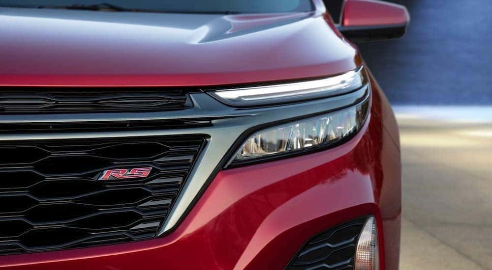 A close up of a red 2022 Chevy Equinox RS shows the drivers side headlight and grille.