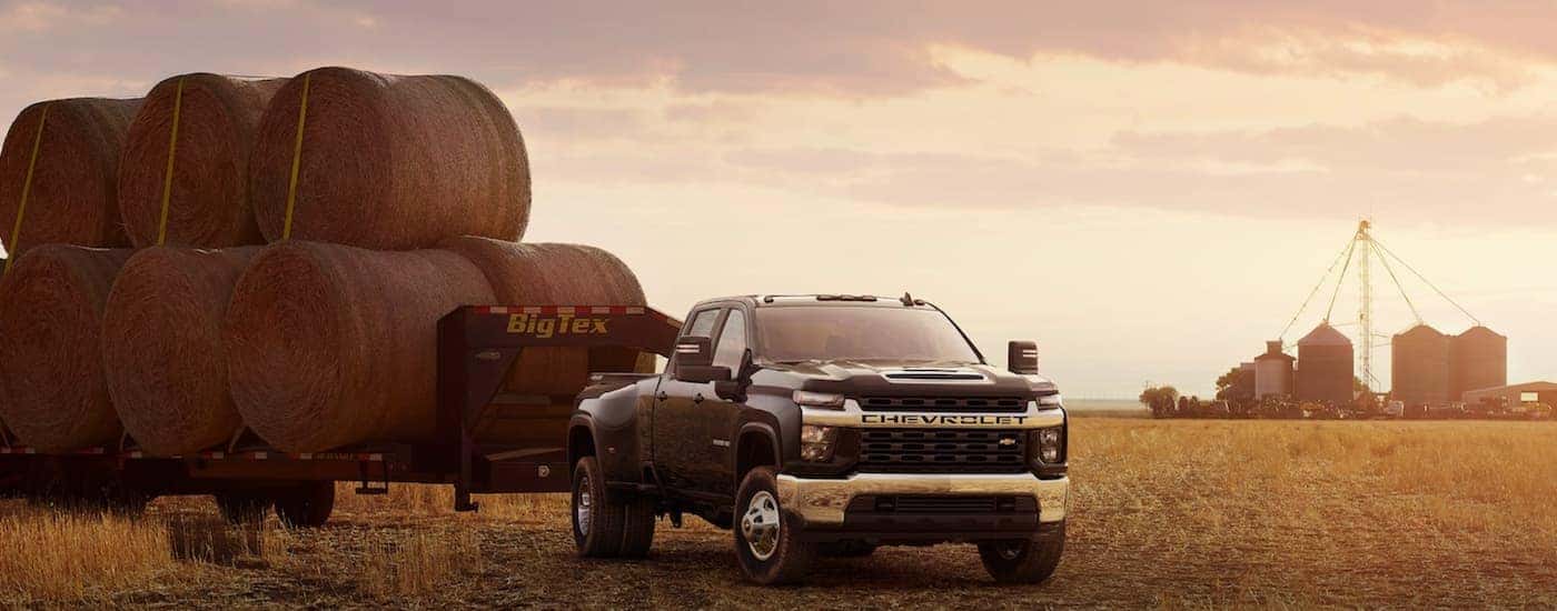 A black 2022 Chevy Silverado 3500 is shown towing a load hay after leaving an Albany Chevy Silverado dealer.