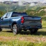 A blue 2022 Chevy Silverado High Country is shown from the rear parked in an open grassy field.