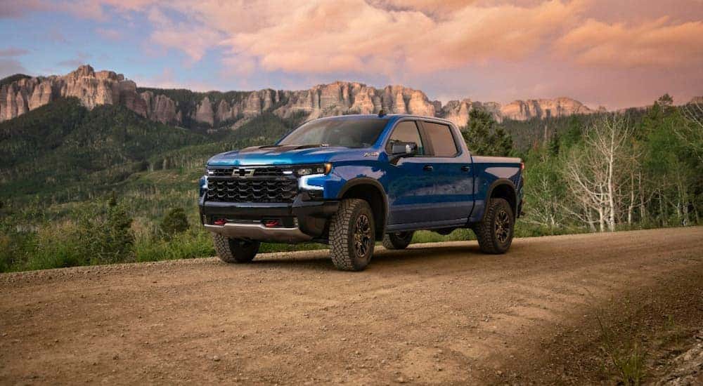 A blue 2022 Chevy Silverado ZR2 is shown parked on a dirt road near the mountains.