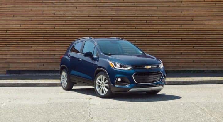 A blue 2018 Chevy Trax is shown parked outside of a certified pre-owned Chevy dealer.