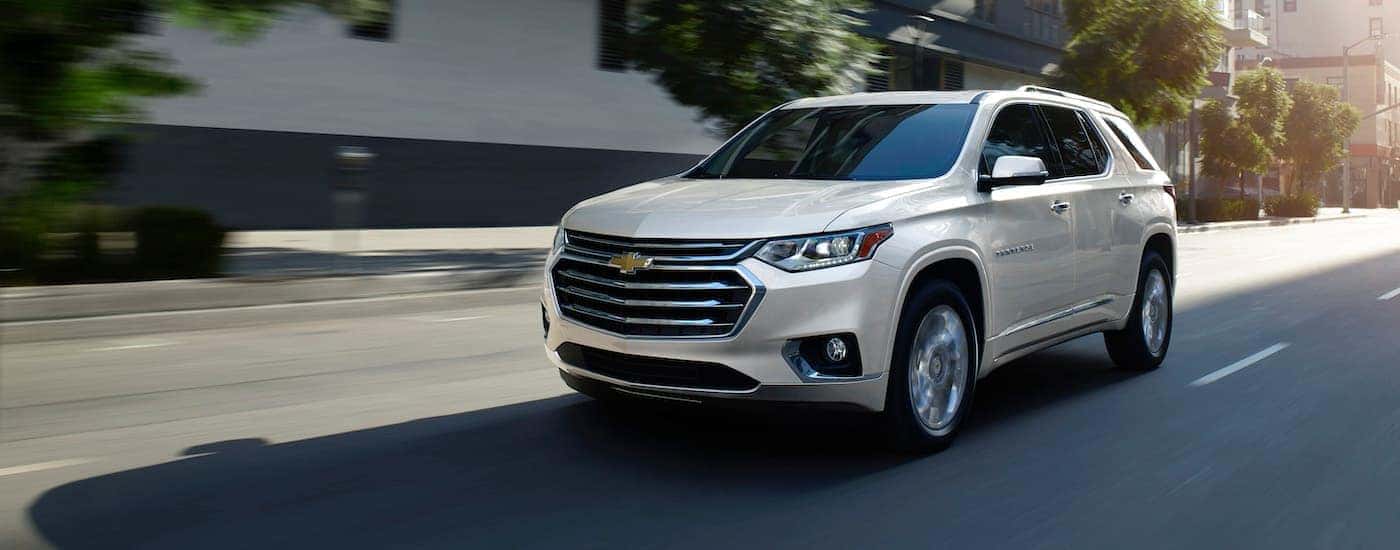 A white 2019 Chevy Traverse is shown driving down a street.