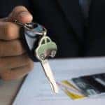 A car salesman is shown holding a set of car keys over paperwork during a Chevy lease return.