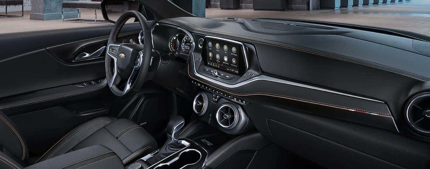 The black interior of a 2022 Chevy Blazer shows the steering wheel and infotainment screen.
