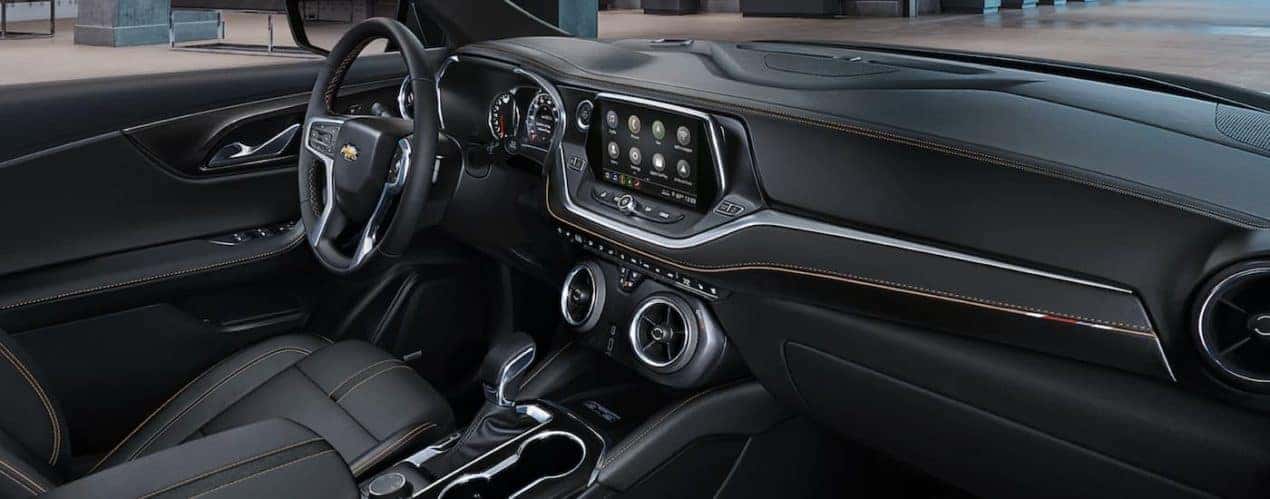 The black interior of a 2022 Chevy Blazer shows the steering wheel and infotainment screen.