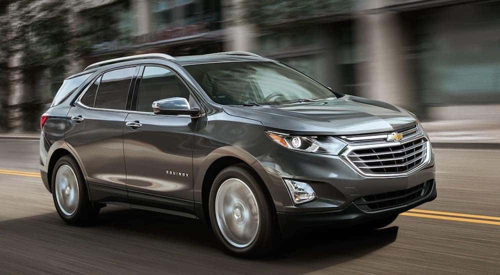 A grey 2019 Chevy Equinox is shown driving down a city street.