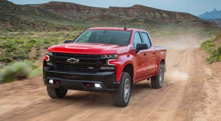 A red 2020 Chevy Silverado 1500LT Trail Boss is shown on a dirt road after leaving a used Chevy Silverado dealership.