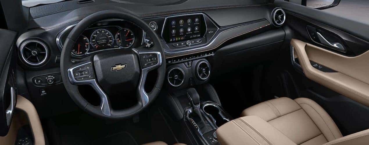 The black interior of a 2022 Chevy Blazer shows the steering wheel and infotainment screen.