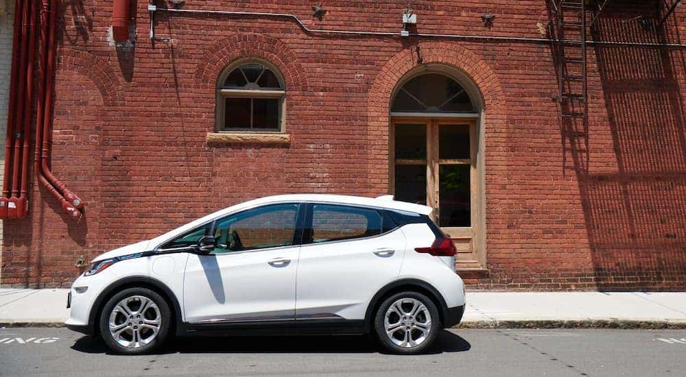 A white 2020 Chevy Bolt EV is shown parked in front of a brick wall.