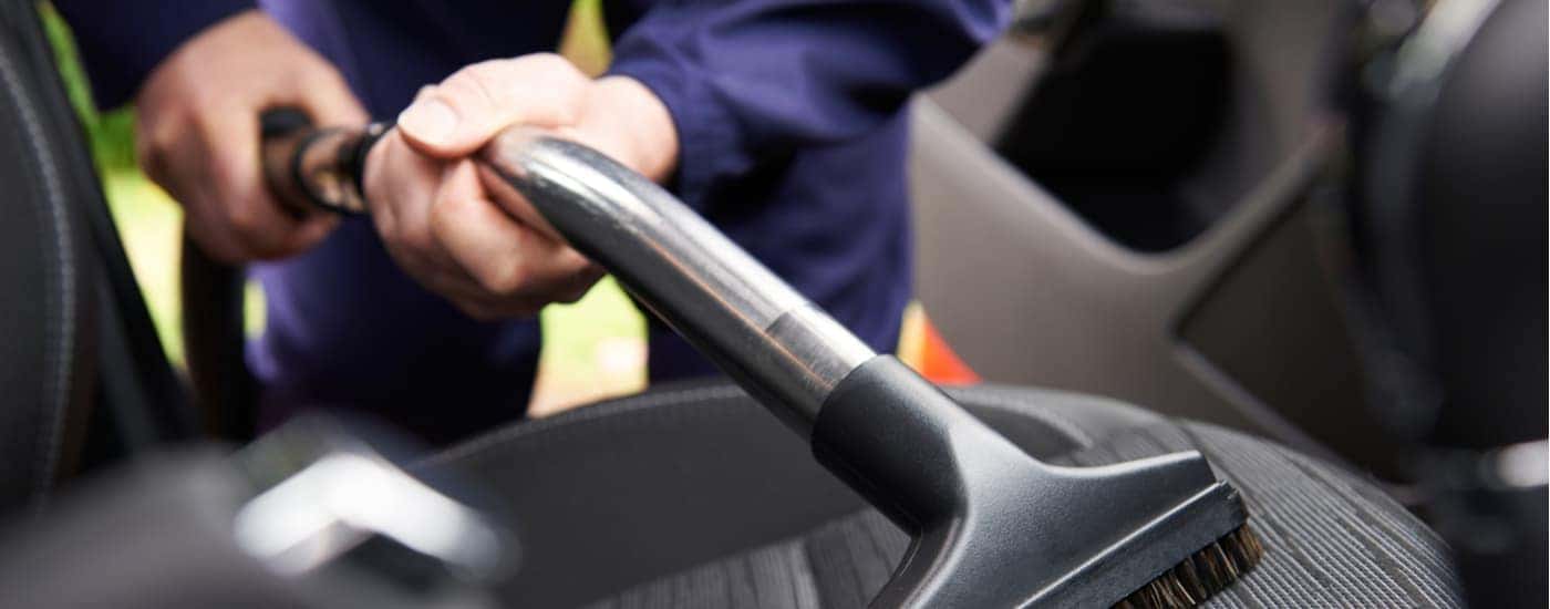 A person is shown vacuuming a vehicle after researching 'how to sell my car.'