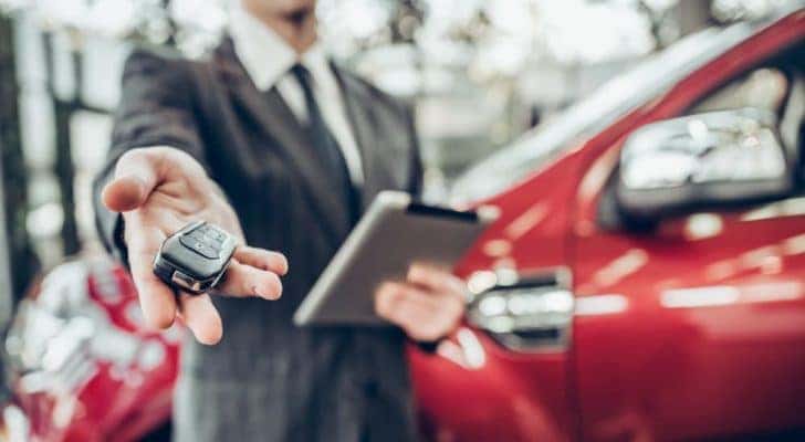 A salesman is shown holding a car key.