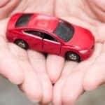 A pair of hands are shown holding a red toy car after searching "sell my car."