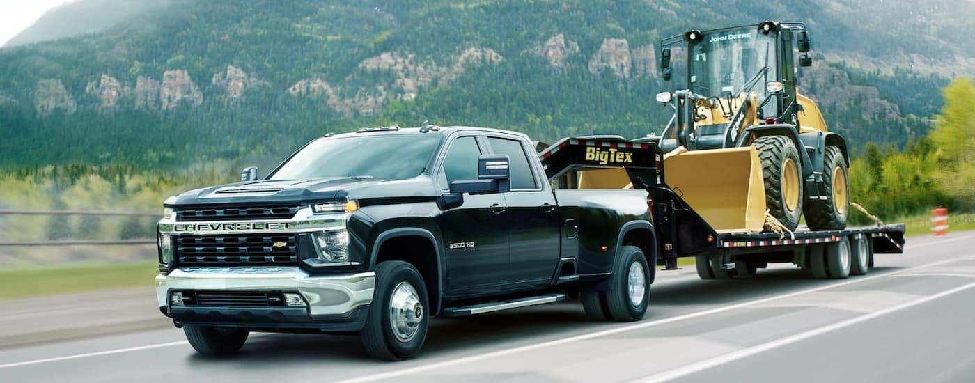 A black 2022 Chevy Silverado 3500HD WT is shown towing heavy machinery after visiting it Chevy 3500HD dealership.