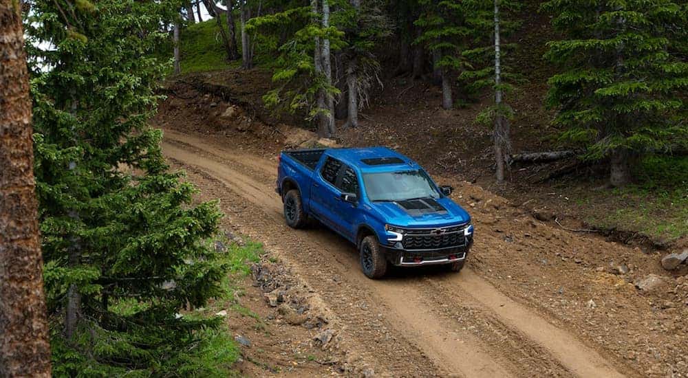 A blue 2022 Chevy Silverado ZR2 is shown driving on a dirt road.