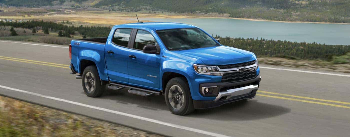 A blue 2022 Chevy Colorado is shown from the side driving past a body of water.