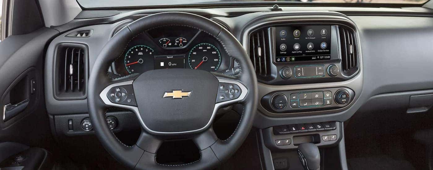 The black interior of a 2022 Chevy Colorado shows the steering wheel and infotainment screen.