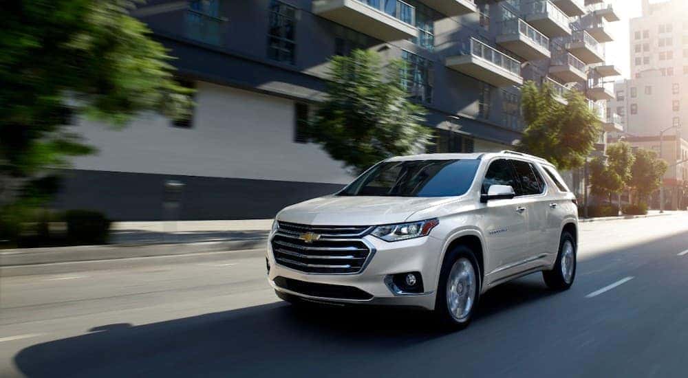 A white 2020 Chevy Traverse High Country is shown driving on a city road.