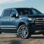 A blue 2022 Chevy Silverado 1500 High Country is shown from an angle parked on dirt.
