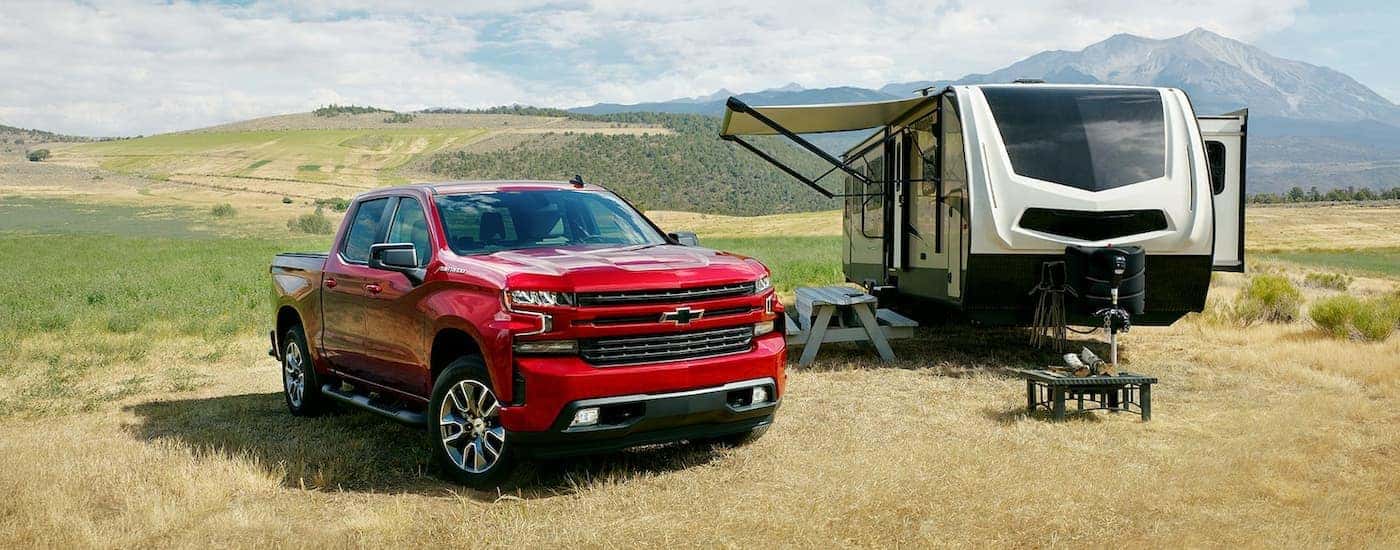 A red 2022 Chevy Silverado 1500 RST Limited is shown parked next to a camper.